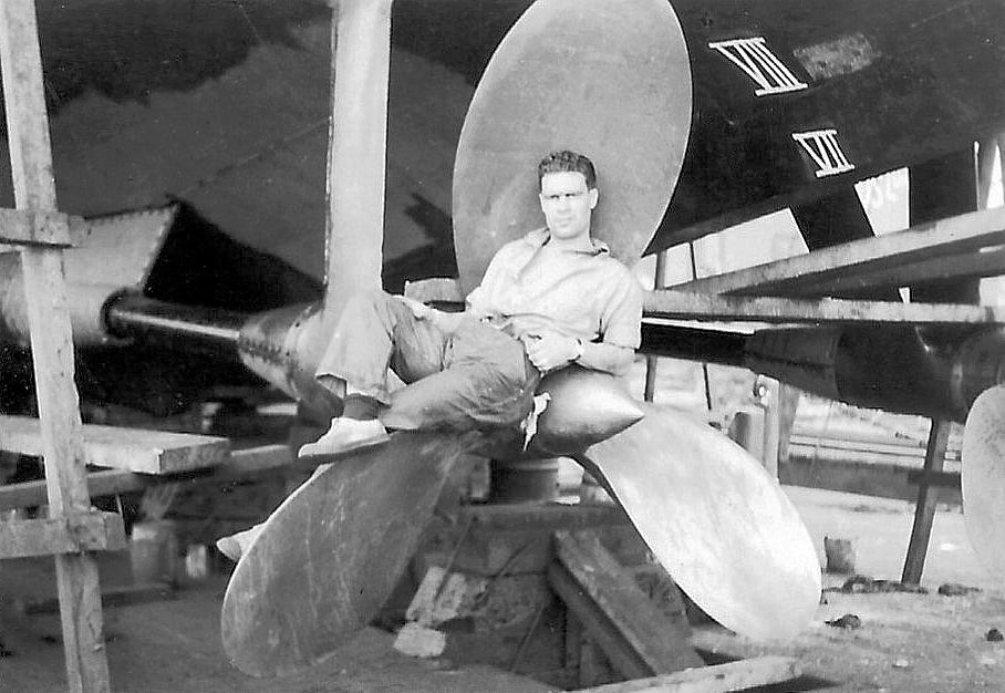 Royal Canadian Navy : Robert Dunn sitting on propeller of HMCS Minas in refit, 1942